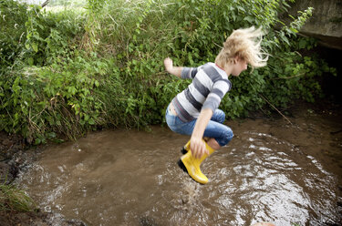 Excited girl jumping into brook - MFRF01062