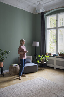 Mature woman at home looking out of window - RBF05847