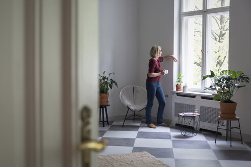 Mature woman at home looking out of window - RBF05849