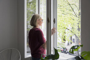Mature woman at home opening the window - RBF05850