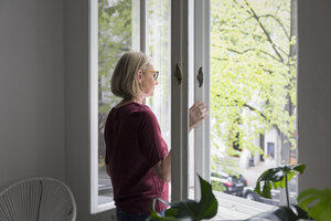 Reife Frau zu Hause beim Öffnen des Fensters - RBF05850