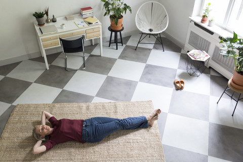 Relaxed mature woman lying on the floor at home stock photo