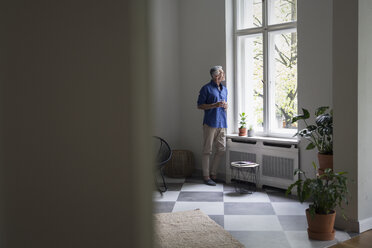 Älterer Mann zu Hause, der aus dem Fenster schaut - RBF05856