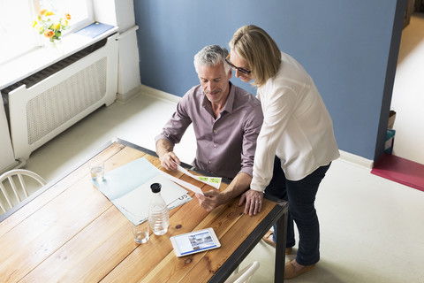 Mature couple with documents and tablet at home stock photo