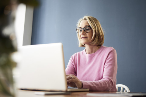 Reife Frau benutzt Laptop zu Hause, lizenzfreies Stockfoto