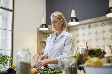 Ältere Frau hackt Paprika in der Küche - RBF05878