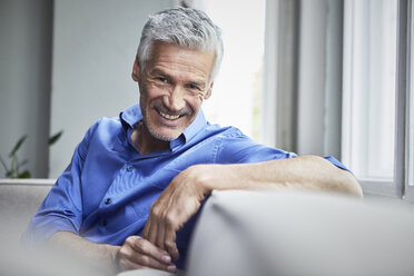 Portrait of smiling mature man sitting on couch at home - RBF05897