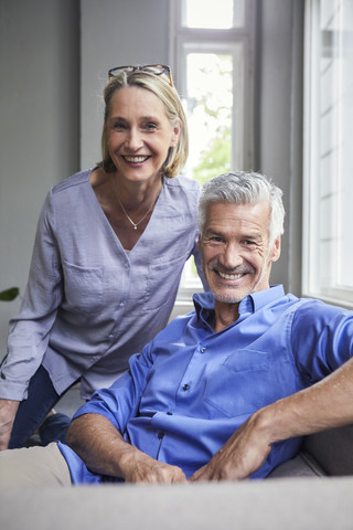 Porträt eines lächelnden reifen Paares auf der Couch zu Hause, lizenzfreies Stockfoto