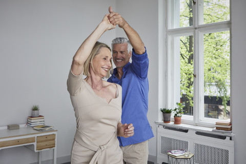 Happy mature couple dancing at home stock photo