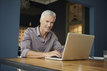Porträt eines reifen Mannes, der einen Laptop auf einem Tisch zu Hause benutzt - RBF05923
