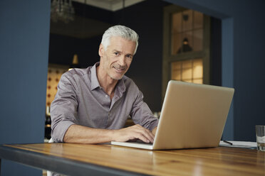 Portrait of mature man using laptop on table at home - RBF05923