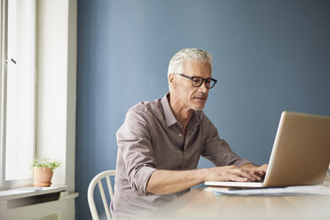 Älterer Mann benutzt Laptop auf Tisch zu Hause - RBF05927