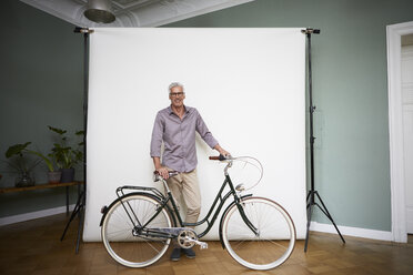 Portait of mature man posing with bicycle at projection screen - RBF05937