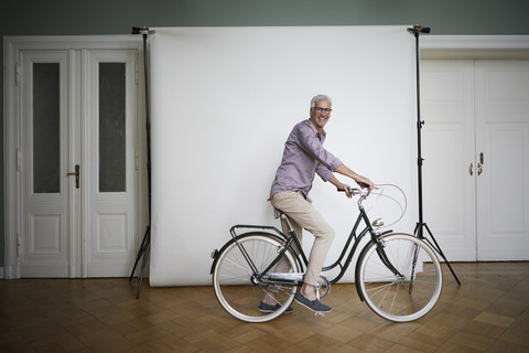 Portait of mature man posing on bicycle at projection screen stock photo