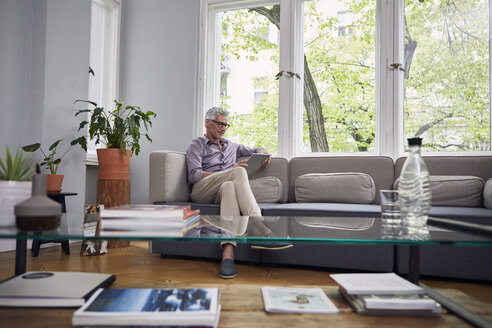 Älterer Mann benutzt Tablet auf der Couch zu Hause - RBF05939