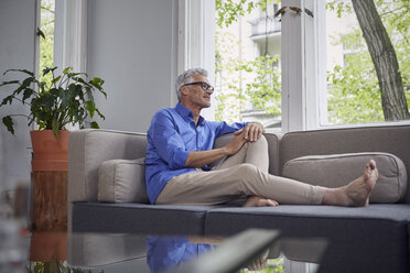 Älterer Mann sitzt zu Hause auf der Couch - RBF05942