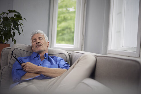 Porträt eines reifen Mannes, der sich zu Hause auf der Couch entspannt - RBF05947