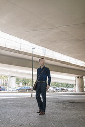Businessman standing at underpass looking around - KNSF02482