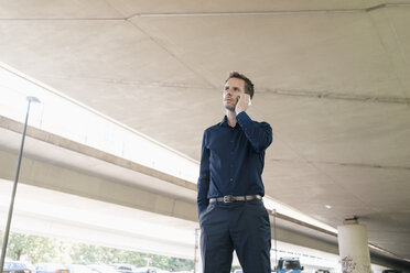 Businessman on cell phone at underpass - KNSF02487