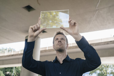 Businessman holding up portable glass device - KNSF02491