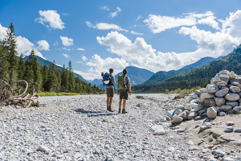 Germany, Bavaria, back view of two hikers standing in dry creek bed looking at view - DIGF02779