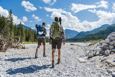 Germany, Bavaria, back view of two hikers walking in dry creek bed - DIGF02780