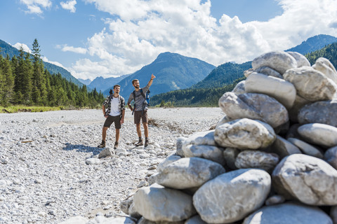 Germany, Bavaria, two hikers standing in dry creek bed looking at view stock photo