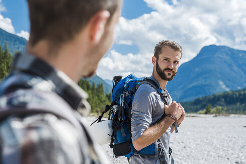 Germany, Bavaria, portrait of young hiker with backpack looking at his friend - DIGF02787