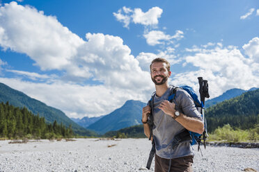 Germany, Bavaria, portrait of young hiker with backpack and hiking poles - DIGF02797