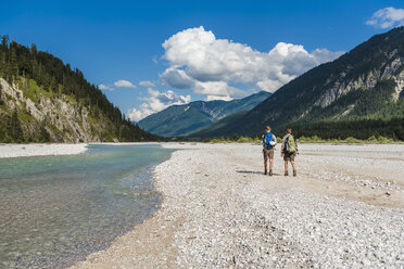 Germany, Bavaria, back view of two hikers with backpacks walking in dry creek bed - DIGF02800