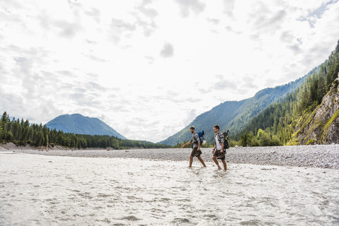 Germany, Bavaria, two hikers with backpacks crossing Isar River stock photo