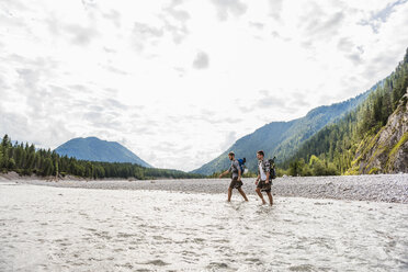 Germany, Bavaria, two hikers with backpacks crossing Isar River - DIGF02803