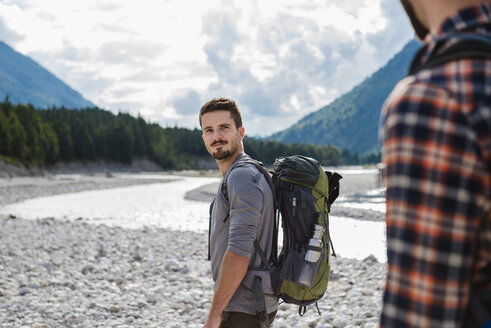 Germany, Bavaria, portrait of young hiker with backpack looking at his friend - DIGF02813