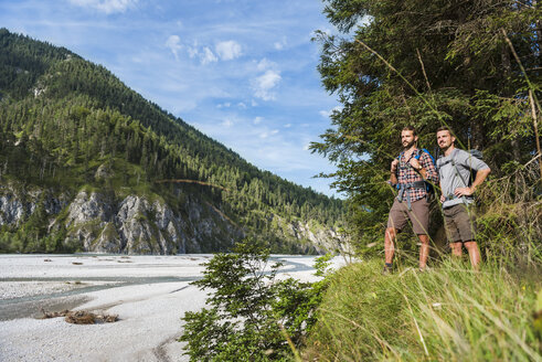 Germany, Bavaria, two young hikers with backpacks looking at view - DIGF02817