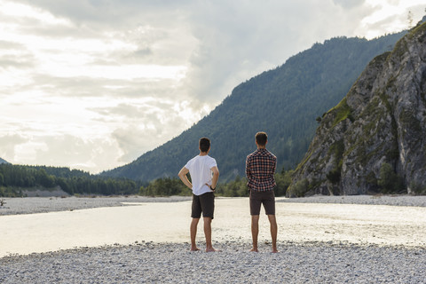 Germany, Bavaria, back view of two friends looking at view at riverside stock photo