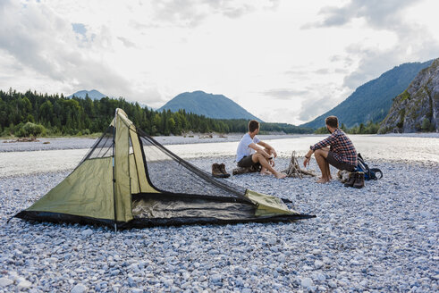 Germany, Bavaria, two hikers camping on gravel bank looking at view - DIGF02829