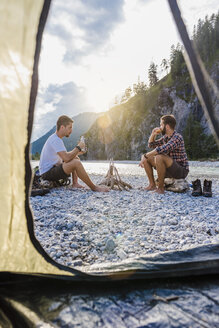Germany, Bavaria, two hikers camping on gravel bank in the evening - DIGF02830
