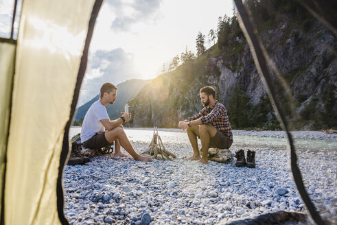 Germany, Bavaria, two hikers camping on gravel bank in the evening - DIGF02831