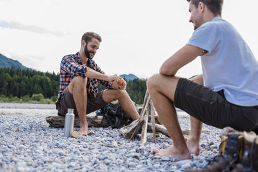 Germany, Bavaria, two hikers having a rest at camp fire on gravel bank - DIGF02836