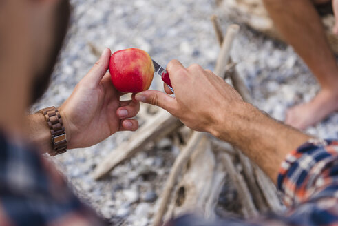 Man's hand cutting apple at camp fire - DIGF02837