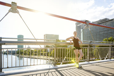 Deutschland, Frankfurt, sportliche junge Frau auf Brücke stehend - PUF00697