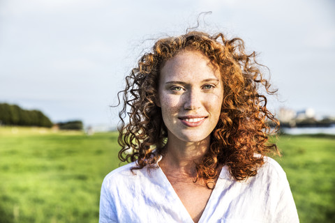 Porträt einer sommersprossigen jungen Frau mit lockigem rotem Haar, lizenzfreies Stockfoto