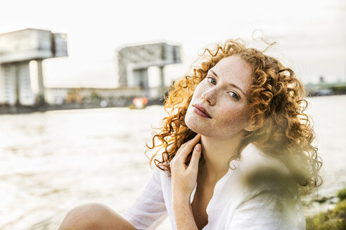 Deutschland, Köln, Porträt einer sommersprossigen jungen Frau mit lockigem rotem Haar - FMKF04399