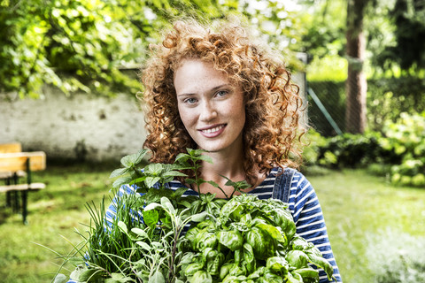 Porträt einer jungen Frau mit frischen Kräutern im Garten, lizenzfreies Stockfoto