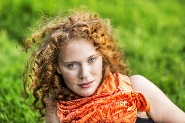 Portrait of freckled young woman with curly red hair wearing orange scarf - FMKF04419