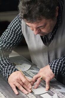 Schuhmacher bei der Arbeit an einer Schablone in seiner Werkstatt - IGGF00140