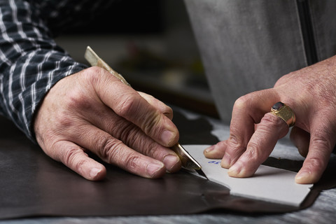 Nahaufnahme eines Schuhmachers bei der Arbeit an einer Schablone in seiner Werkstatt, lizenzfreies Stockfoto