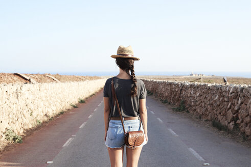 Spanien, Menorca, Rückansicht eines Alleinreisenden auf der Landstraße - IGGF00145