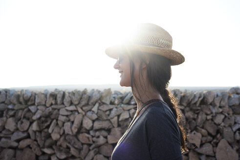 Spanien, Menorca, lächelnder Einzelreisender mit Strohhut im Gegenlicht - IGGF00149