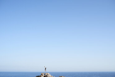 Spanien, glückliche Frau springt in die Luft vor blauem Himmel - IGGF00152